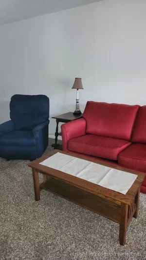 Living room with red couch, blue recliner, wooden coffee table, and lamp.