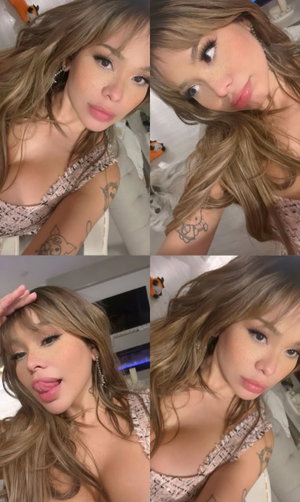 Woman with wavy brown hair in lace top, indoor selfie.