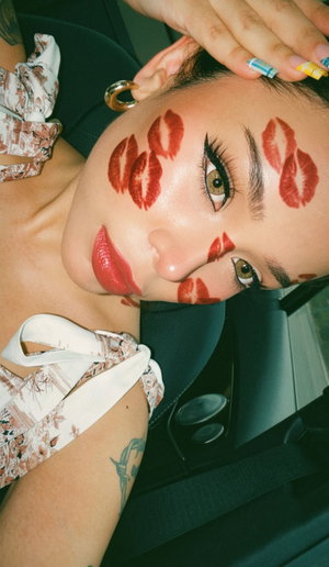 Woman with tattoos in off-shoulder floral top in car.