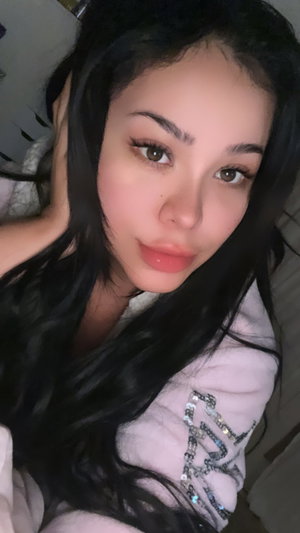 Asian woman with long black hair in pink robe indoors.