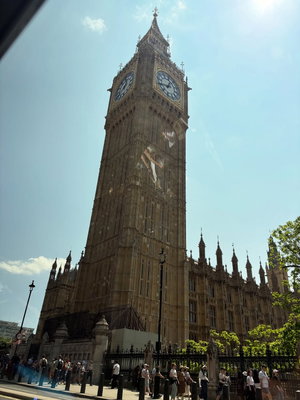 Big Ben tower with tourists at its base under blue sky.