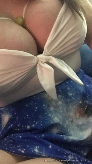 Woman in white top and blue patterned skirt, close-up on chest and waist.