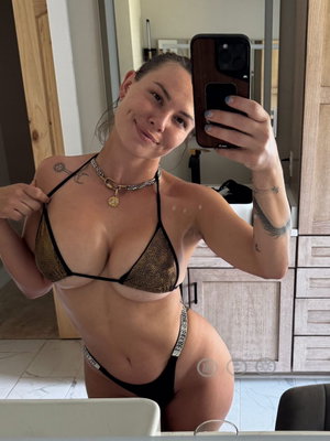 Woman in bikini taking mirror selfie indoors.