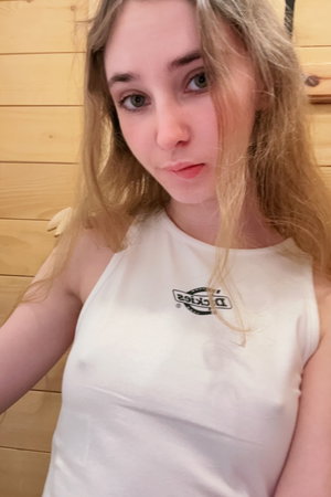 Blonde woman in white tank top against wood panels.
