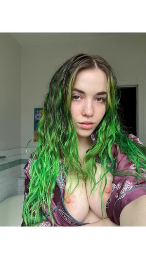 Woman with green hair in purple robe, bare chest, indoors.