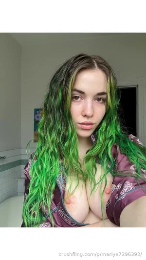 Woman with green hair, wearing purple robe, bare chest, in bathroom.