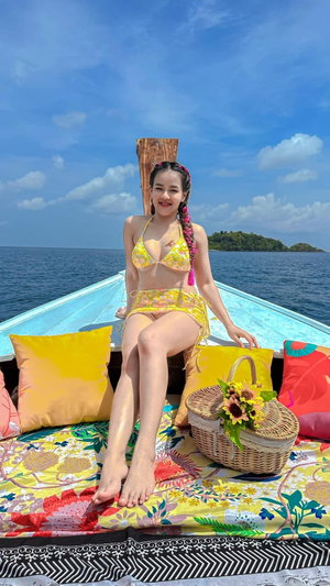 Woman in floral bikini sitting on boat at sea.