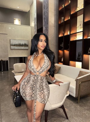 Woman in snakeskin dress posing in modern living room with furniture and decor.