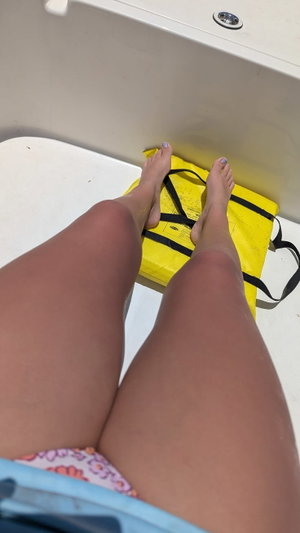Woman's legs in colorful underwear, standing on yellow bag in bathroom.