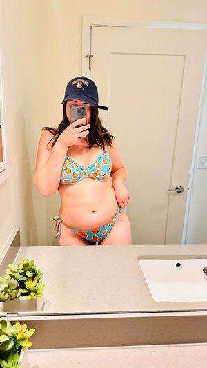 Woman in bikini taking mirror selfie in bathroom.