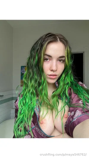 Woman with green hair, wearing purple robe, bare chest, indoors.