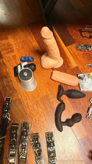 Various adult toys and restraints on a wooden floor.