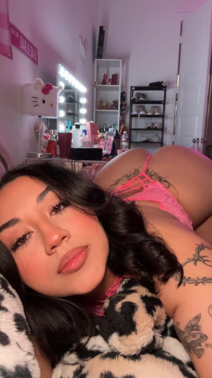 Brunette in pink lingerie lying on bed in bedroom.