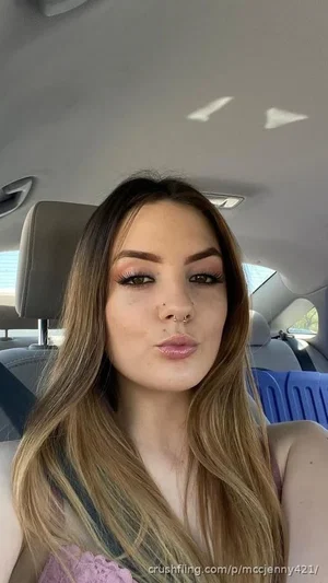 Woman with long ombre hair and nose ring, wearing pink lace top, sitting in car.