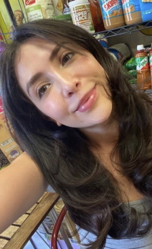 Woman with long dark hair taking selfie in pantry.