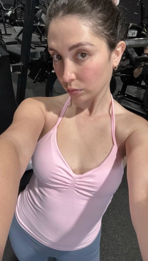 Woman in pink top taking selfie in gym.