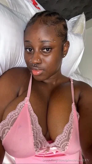 Woman in pink lace lingerie lying on a bed with white pillows.
