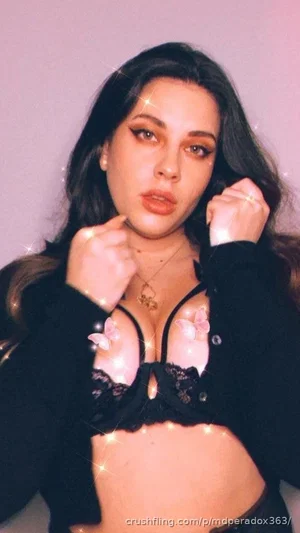 Woman with dark hair in black lace lingerie and cardigan, posing indoors with sparkles.