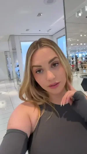 Blonde woman in black off-shoulder top in store.