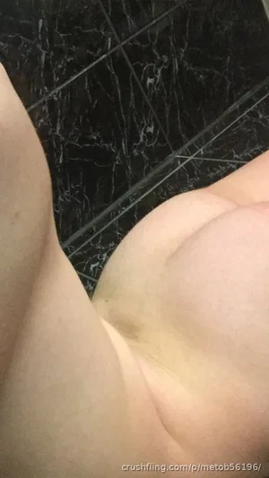 Close-up of bare buttocks on dark marble tiles, indoor setting.