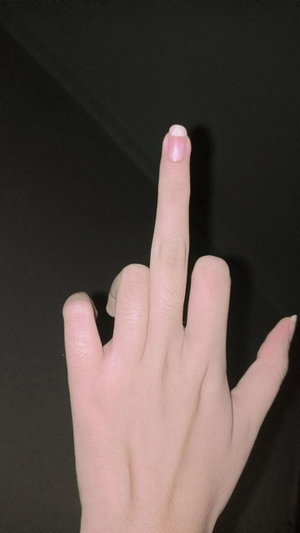 Close-up of a hand with manicured nails against a dark background.