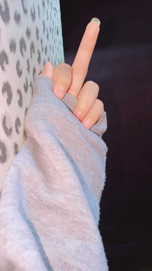 Hand in gray sweater making middle finger gesture near leopard print fabric.