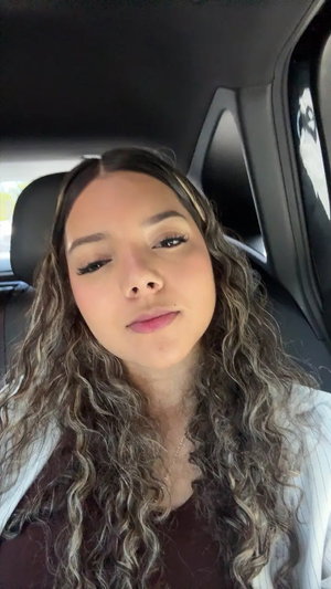 Woman with long wavy hair in car selfie.