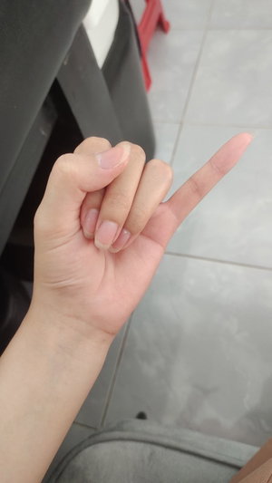 Hand making a peace sign, tiled floor background, partial view of furniture.