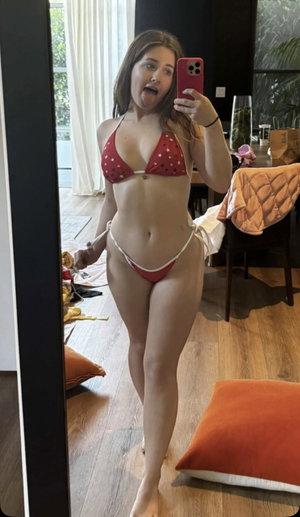 Woman in red star-patterned bikini takes mirror selfie in bedroom.