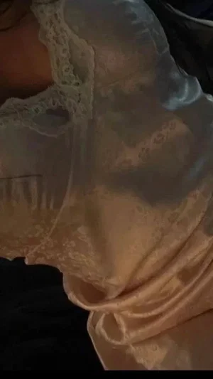 Woman in light pink lace lingerie, indoor setting, close-up on chest and shoulder.