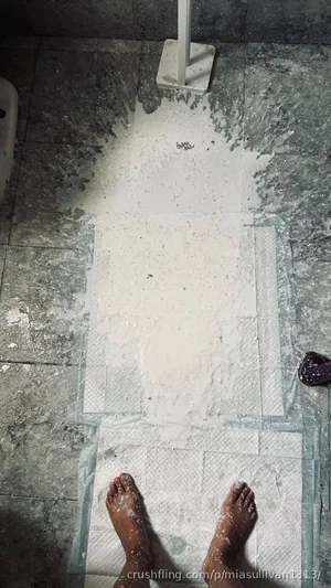 Feet on paper towels in a tiled bathroom, covered in white powder.