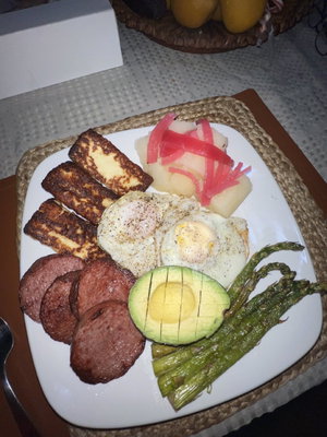 Breakfast plate with eggs, avocado, asparagus and sausage.