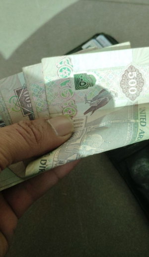 Hand holding UAE 500 dirham banknotes, close-up view.