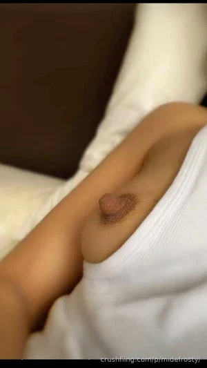 Woman with visible nipple under white top, lying on bed.