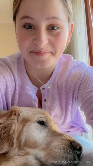 Woman in light purple button-up shirt with dog, indoor setting.