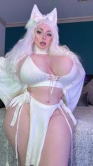 Woman in white cat ears and lingerie posing on bed indoors.