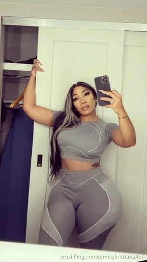 Woman in gray athletic wear taking mirror selfie in bedroom.