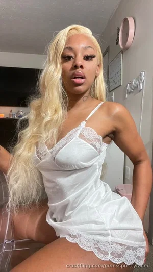 Woman with long blonde hair in white lace lingerie posing indoors.