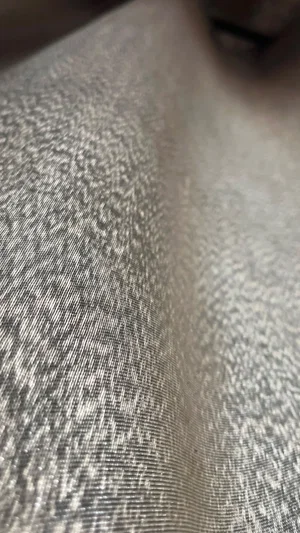 Close-up of textured fabric, possibly clothing, with partial skin visible at edge.