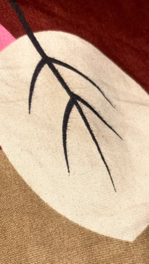 Close-up of fabric with embroidered leaf design in black thread.