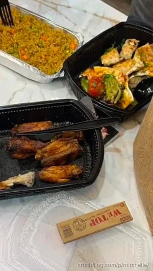Takeout food in black containers on a marble surface, including rice, chicken, and wings.