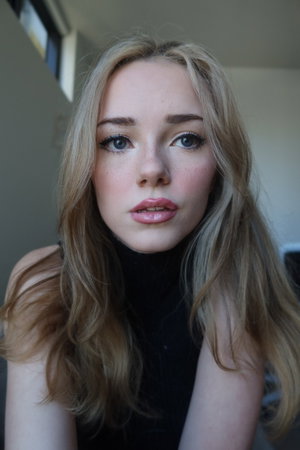 Slim blonde woman in black turtleneck indoors.