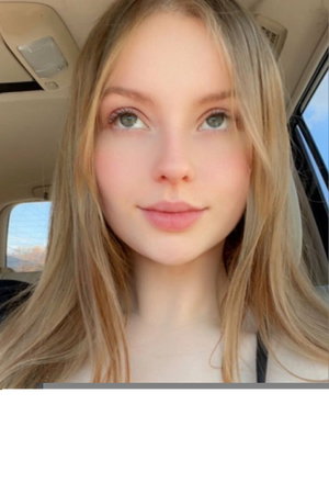 Blonde woman smiling in car selfie.