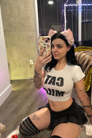 Dark haired woman in crop top taking selfie indoors with cat ears.