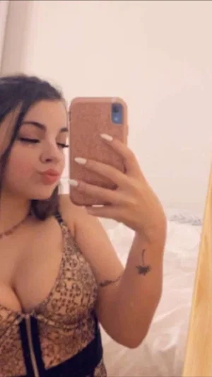 Woman in lace lingerie taking mirror selfie in bedroom.