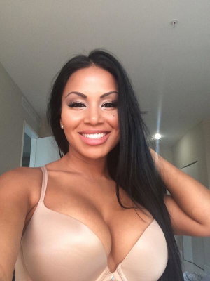 Woman with long dark hair wearing beige bra indoors.