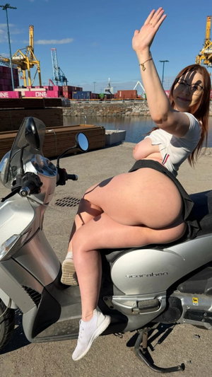 Woman with glasses in white top on scooter outdoors.
