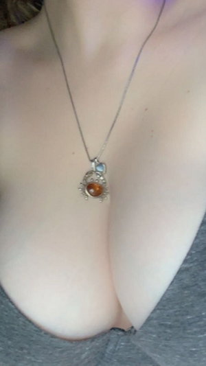 Woman in gray top with necklace, showing chest area.