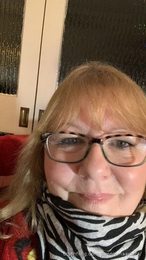 Woman with blonde hair and glasses wearing a zebra-print scarf indoors.