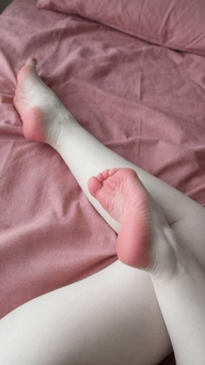 Bare legs on pink bedding, close-up view of feet and lower legs.